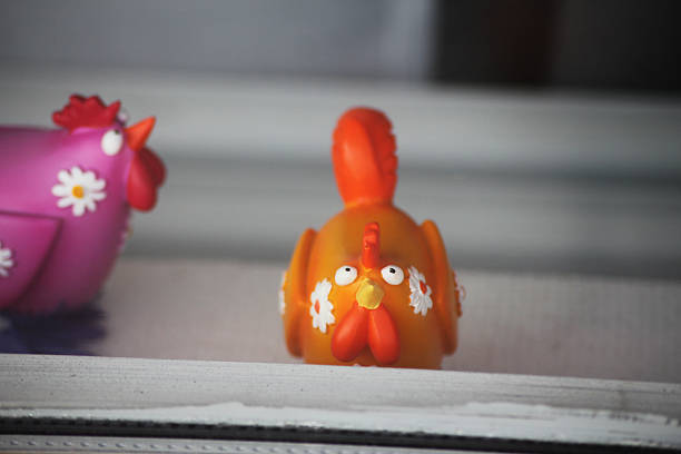 Two colorful porcelain roosters in a window