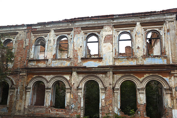 Roofless falling apart old abandoned ruined building  with empty windows and plaster going off the walls
