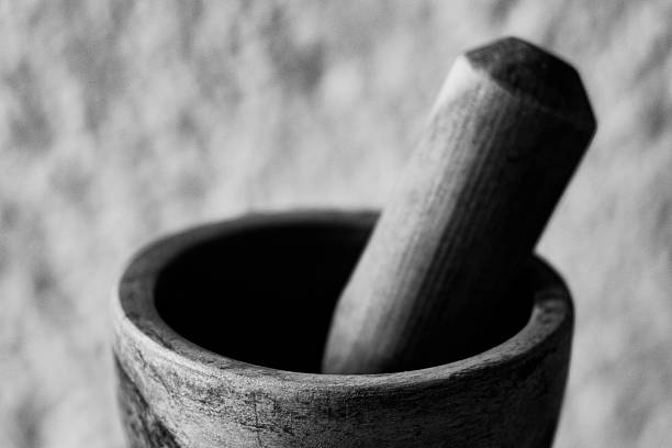 Close-up of a handcrafted wooden mortar and pestle set against a textured black-and-white background. Highlights rustic craftsmanship, perfect for themes of culinary tradition and artisanal tools.