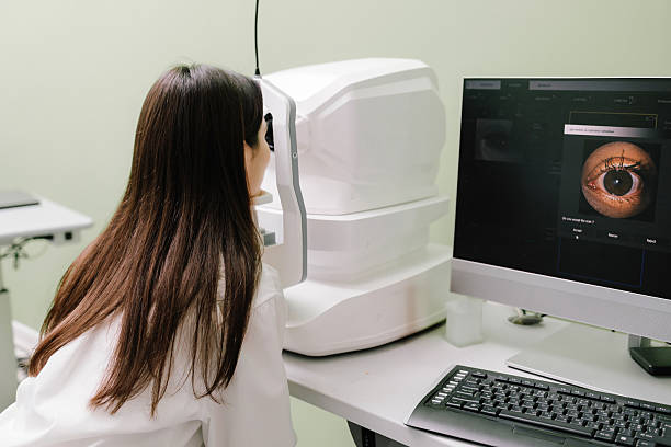 istock Examination of eyes of patient using optical coherence tomograph. Ophthalmologist is scanning cornea of girl patient. Optical coherence tomography OCT scan to create pictures of the back of eye. 2208005295