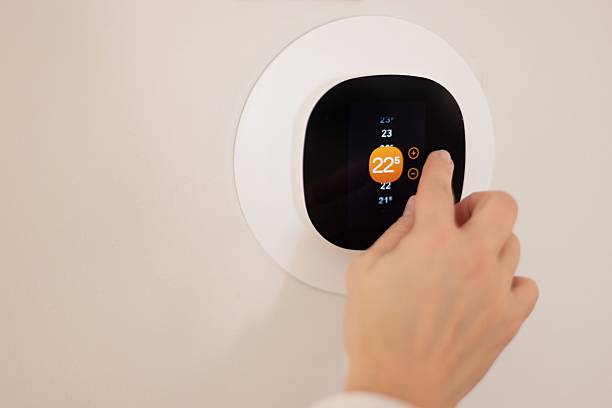 istock Person Adjusting Smart Thermostat on Wall for Comfortable Room Temperature 2208007475