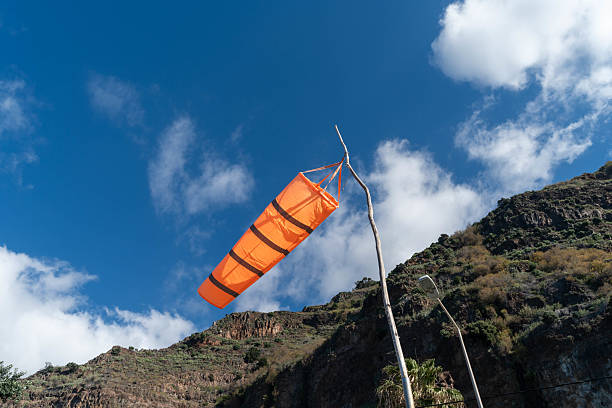 An orange windsock on rooftop of the industrial plant, it using to identify windy speed and direction. Industrial safety equipment object photo.