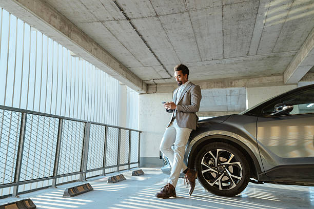 istock Business professional using a smartphone next to a modern car in a garage 2208012678