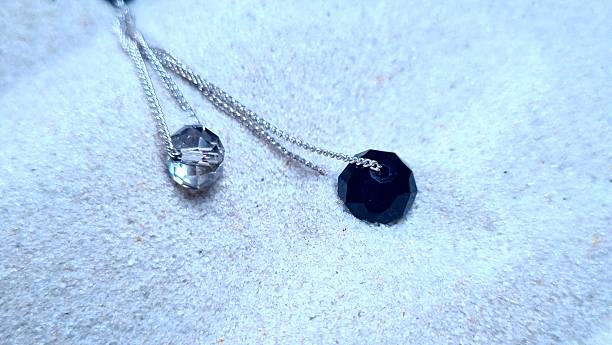 Modern Monochrome Earring with Contrasting White and Black Crystals on Silver Chains Over Textured Sand: Bold Jewelry Photography for Fashion Editorials, Beach-Themed Ads, and Minimalist Accessory Stock Content