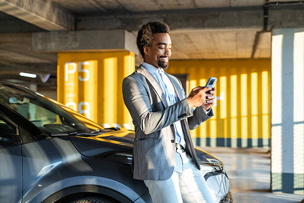 istock Business professional using smartphone near car in parking structure 2208013692