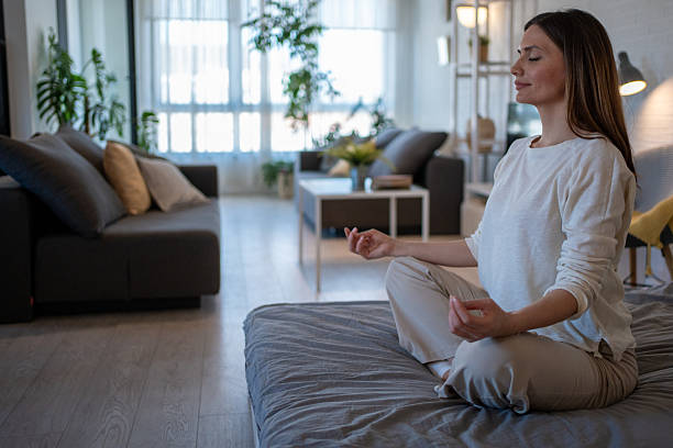 istock Serene woman meditating on bed in cozy home: finding inner peace and mindfulness 2208019419