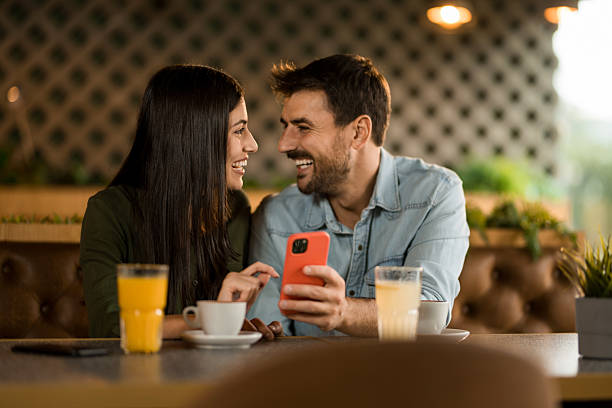 istock Happy couple using smart phone in cafe. 2208026089