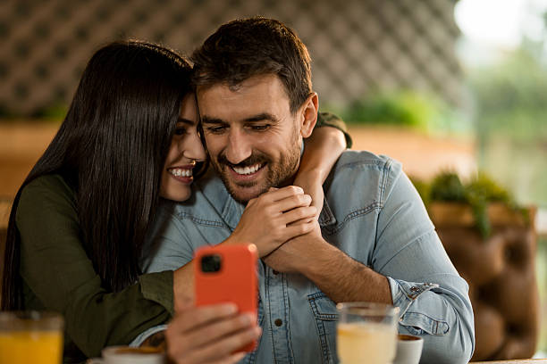 istock Happy couple using smart phone in cafe. 2208026326
