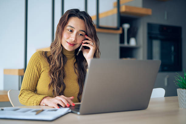 istock Asian woman using phone and laptop to work from home. 2208028343