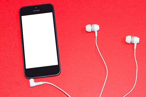 A smartphone with a blank screen and a wired headset on a red background. Auditory reading represented in a minimalist image.