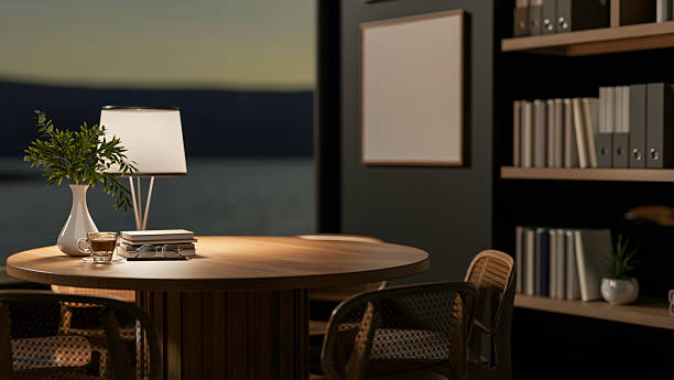 A coffee cup and books on wooden table under a lamp light in dim room. Study or Working at night.