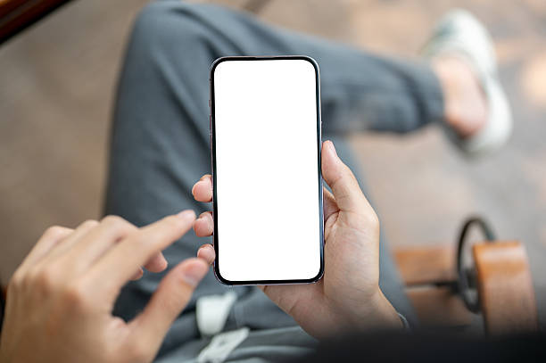 istock A hand holding smartphone with finger pointing at the white screen, sitting cross legged on chair. 2208050492