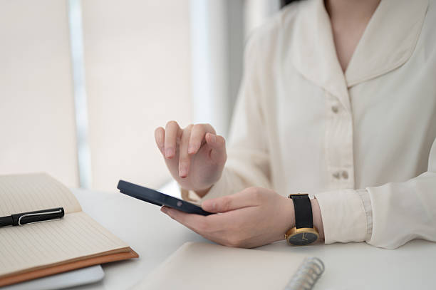 istock Close up of a female office worker hand hovering over phone while sitting at working table in office 2208053217