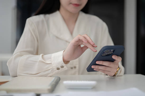 istock Close up of a female office worker hand hovering over phone while sitting at working table in office 2208053234