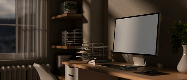 istock A blank screen computer on wooden table with study or working materials in the dim lit room. 2208054596