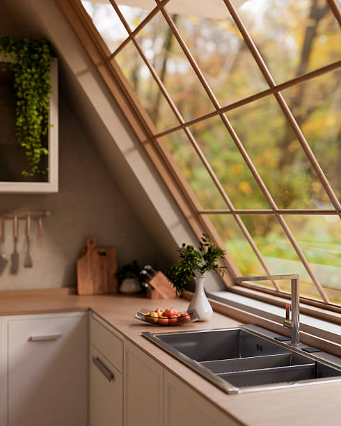 A glass plate with apples on wooden counter with integrated sink under roof window with garden view.