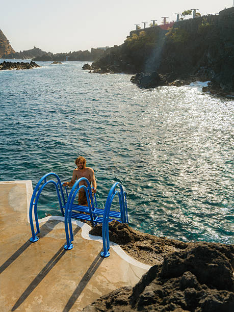 Cheerful man  jumping into the sea from diving board  on Madeira island