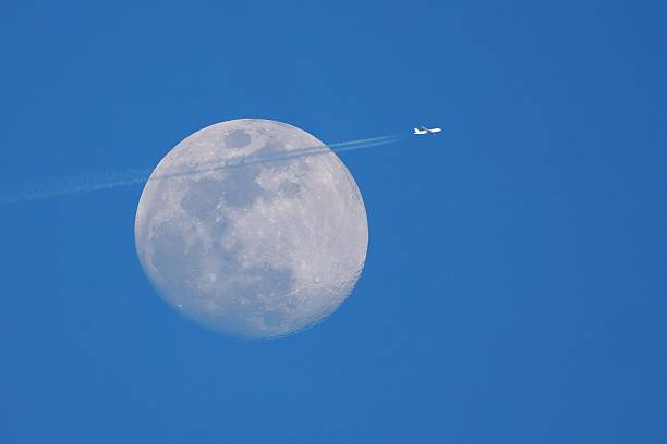 istock Plane flying past the full moon in a clear sky. 2208057555