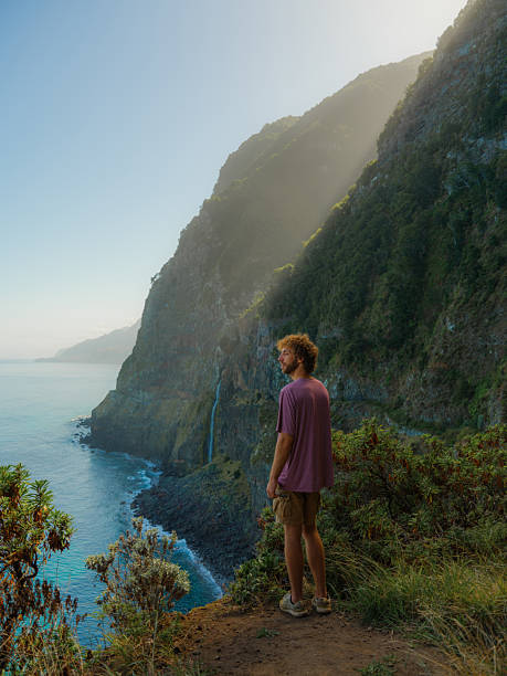istock Man looking at epic waterfall falling into Atlantic ocean on Madeira island 2208061367