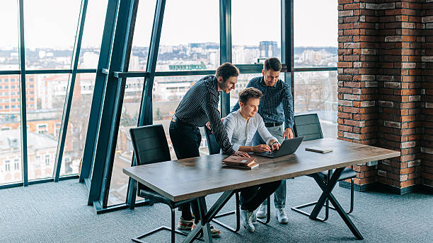 istock Colleagues collaborating around a laptop in a modern office for brainstorming ideas and data analysis 2208063310