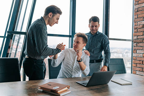 istock Celebrating teamwork and success in a modern office setting with young professionals collaborating on laptops 2208063320