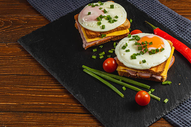 istock Tasty breakfast sandwich with eggs, ham, and veggies on slate 2208064739