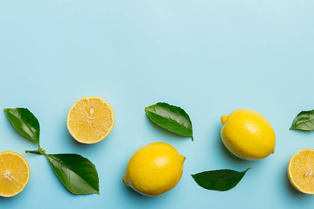 istock Many fresh ripe lemons with green leaves on colored background, top view, space for text 2208065862