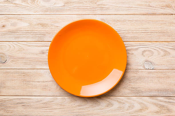 istock Top view of empty orange plate on wooden background. Empty space for your design 2208065901