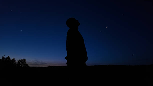 istock Silhouette of a man observing Milky Way stars, planets and other celestial objects from a dark countryside location. 2208069010