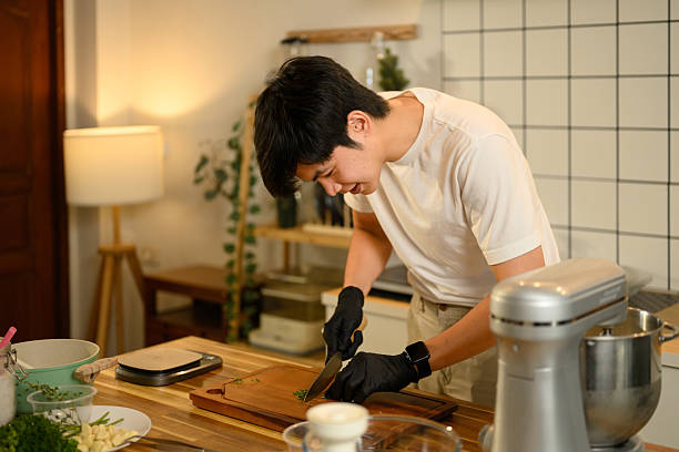 istock Smiling young man chopping fresh parsley on wooden cutting board while preparing garlic butter in a cozy kitchen 2208069822