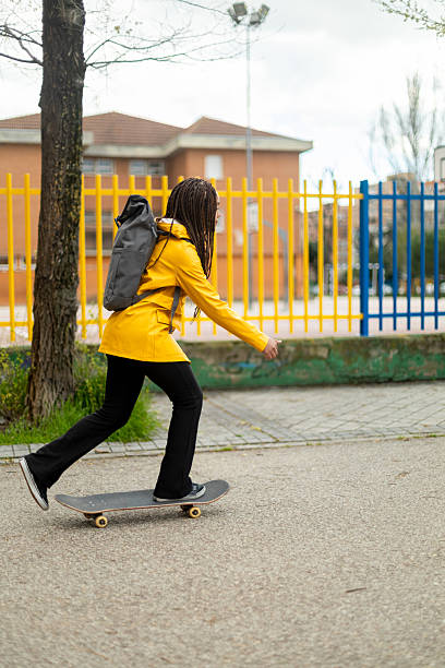 istock Young woman skateboarding in a yellow raincoat 2208070669