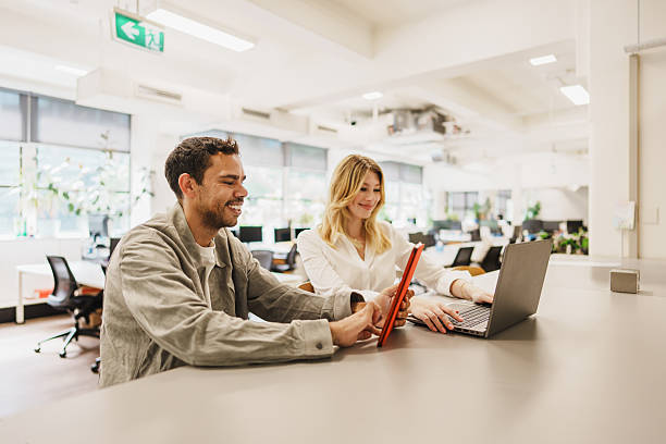 Smiling young professionals collaborating with digital devices in a modern office