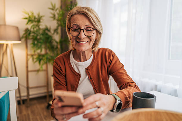 istock Smiling senior woman using smartphone at home 2208072646