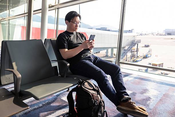 istock Asian male backpacker traveling alone using mobile phone to search for information online in airport waiting area 2208073706