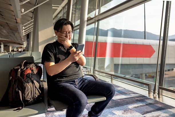 istock Asian male backpacker traveling alone using mobile phone to search for information online in airport waiting area 2208073721