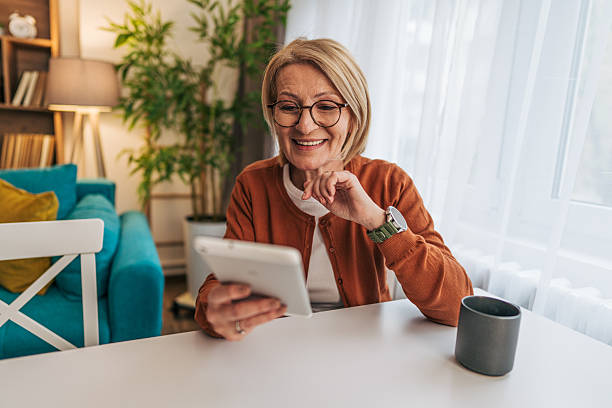 istock Smiling senior woman using digital tablet at home 2208074424