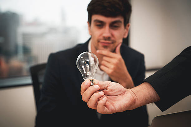 istock A man holding a light bulb in his hand 2208077202