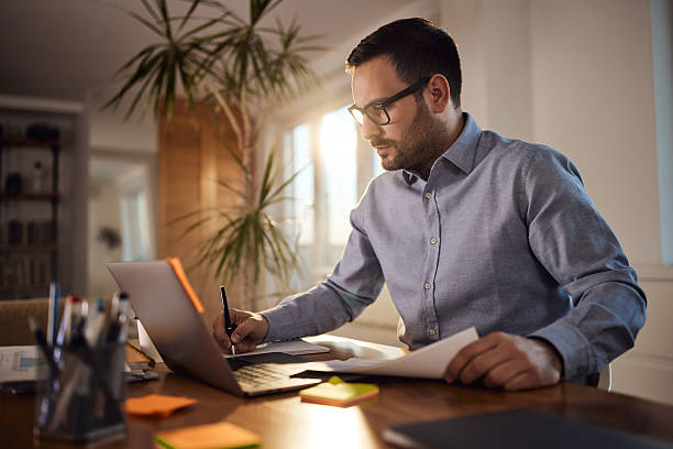 istock Male entrepreneur taking notes while working on laptop at home office. 2208077409