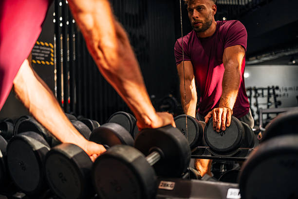 istock Man Observing Gym Dumbbells Preparing for Weightlifting Exercise 2208077492