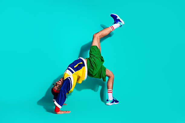 Hip-Hop Dancer Doing Handstand Against White Background