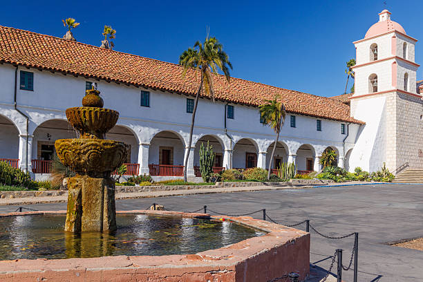 Water trickles into a fountain pool built into a stone wall with a decorative arched window framed with ceramic tile.