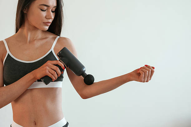 istock Process of doing self massage using massager. Young woman with slim body type is indoors 2208082158