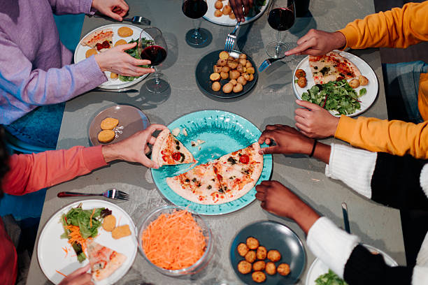 istock Friends sharing pizza and side dishes at dinner table 2208084258