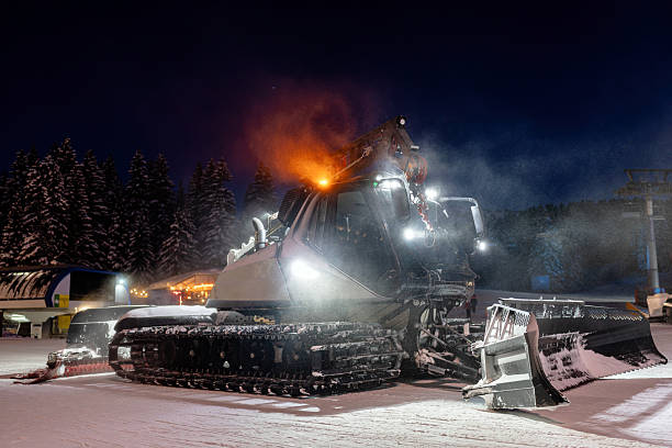 istock Snow grooming machine leveling ski slopes during twilight in snowy mountains 2208084734