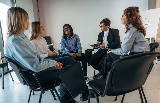 istock Sitting and talking. People are in group psychological support room together 2208084735