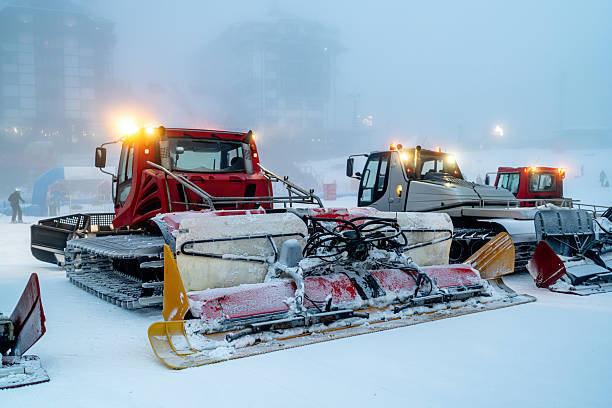 istock Snow grooming vehicles parked on a misty ski slope at dusk 2208085636