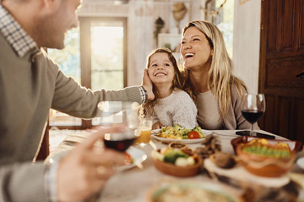 istock Cheerful mother and daughter talking to a father at dining table. 2208087621
