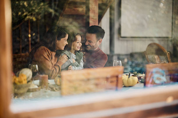 istock Happy parents enjoying with their daughter at dining table. 2208089842