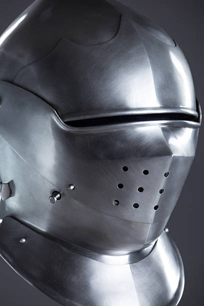 istock Polished Silver Medieval Armet Helmet with Perforated Visor. This shiny silver armet features a rounded skull, a protective bevor, and a visor with multiple small perforations. 2208089894