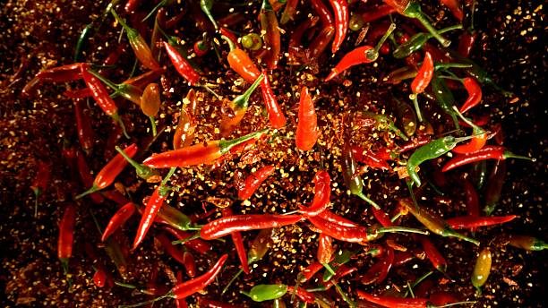 istock Group of coloured chilli peppers flying on black background. 2208090080